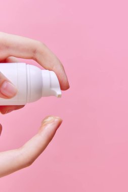 Kadın el sıkma kreminin yakın plan görüntüsü, İşaretlenmemiş şişeden eller için jöle, parmak üzerinde pastel pembe arka plan. Vücut ve cilt bakımı, kaplıca, cilt bakımı. İlan için alanı kopyala