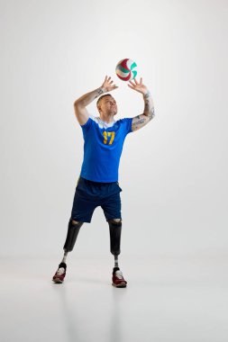 Protez bacaklı, kendine güveni tam bir genç üniformalı adam voleybol topunu hareket halinde vuruyor. Engelli insanlar için özel bir spor. Spor, oyuncu, sağlık, vücut bakımı kavramı.