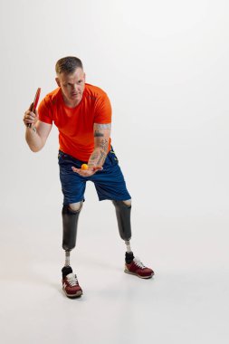 Üniformalı prostetik bacaklı kendine güvenen adam masa tenisi raketiyle topu hareket ettiriyor. Engelli insanlar için özel bir spor. Spor, oyuncu, sağlık, vücut bakımı kavramı