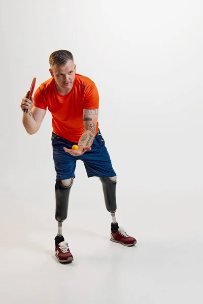 stock image Confident man with prothesic legs in uniform pitches ball in motion with table tennis racket. Inclusive sport for people with disabilities. concept of sport, player, medical, health, body care