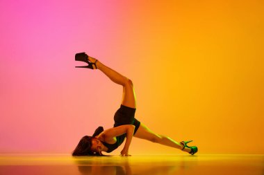 Renkli neon ışıkta senkronize dalga şeklinde poz veren genç ve formda bir bayan dansçı. Çağdaş dans tarzı, sanat, estetik, hobi, yaratıcılık kavramı