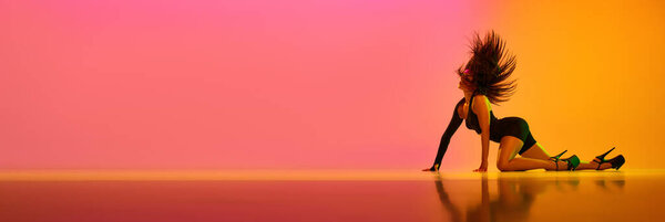 Young female dancer performing on stage in hight heels dance style over gradient pink orange background in neon light. Concept of contemporary dance style, aesthetics, hobby, creativity. banner