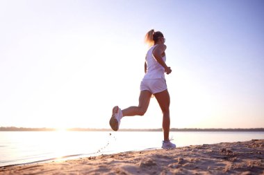 Dikiz aynasından genç sağlıklı bir kadının tam boy portresi, eğitim, gün doğumunda nehrin kıyısında koşmak. Sabah fitness egzersizi. Spor anlayışı, eğlence, sağlıklı yaşam tarzı, hobi.