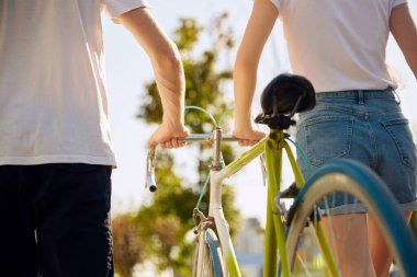 Parkta bisiklete binen aktif genç bir çiftin kesilmiş fotoğrafı. Aşk yürüyüşü yapan sevimli, hoş bisikletçiler. İki arkadaş birlikte zaman geçirirken birbirlerine aşık oluyorlar. Aşk kavramı, insanlar, doğa.