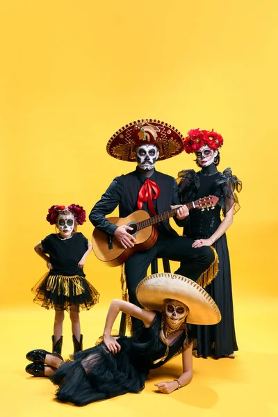 Dead mexican family with sombrero on halloween party. Studio shot of zombies isolated on yellow background. day of the dead. trick or treat. Concept of autumn, holidays, horror, body art. Ad.