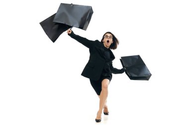 Alışverişkolik. Moda ofis kıyafeti giymiş, alışveriş merkezine büyük çantalarla koşan genç bir kadının tam boy portresi. Kara Cuma kavramı, Siber Pazartesi, moda, güzellik, satın alma, satış.