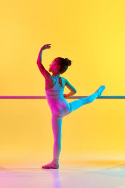 Dikiz manzaralı, küçük şirin çocuk balerin kızı sivri uçlu ayakkabılı klasik varyasyon eğitimi karışık neon ışıklardaki barre performansından önce. Güzellik, moda, hobi, aksiyon kavramı. ad