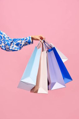 Satış teklifi. Kara Cuma. Alışveriş indirimi. Kadının el ele tutuşup pembe boş arkaplanda izole edilmiş mavi çantalar alması. Alışveriş konsepti, siber pazartesi. reklam için boşluk kopyala