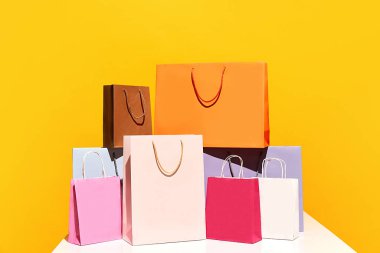 Satış teklifi. Kara Cuma. Alışveriş teslimatı. Sarı arka planda izole edilmiş renkli kağıt poşet piramit grubu. Moda konsepti, güzellik, satış elemanı, marka, trend. reklam için boşluk kopyala