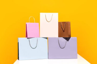 Satış teklifi. Kara Cuma. Alışveriş teslimatı. Sarı arka planda izole edilmiş beş renkli kağıt çanta satın alın. Moda, güzellik, dükkan, satış elemanı, marka, trend konsepti. reklam için boşluk kopyala