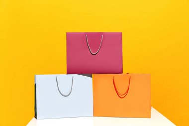 Büyük indirim. Kara Cuma. Alışveriş indirimi. Sarı arka planda izole edilmiş renkli kağıt torbaları satın alma piramidi fotoğrafı. Moda, güzellik, dükkan, satış elemanı, marka, trend konsepti. kopyalama alanı. ad