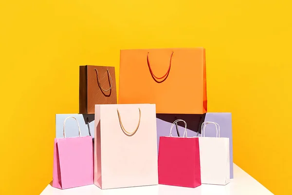 Sale offer. Black Friday. Shopping delivery. Group of purchase colorful paper bags pyramid isolated on yellow background. concept of fashion, beauty, salesperson, brand, trends. copy space for ad