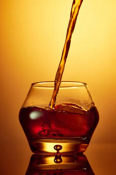 倒入玻璃杯威士忌 朗姆酒 白兰地或杜松子酒 在金色渐变背景上涂上冰块 夜生活 餐馆的概念 — 图库照片