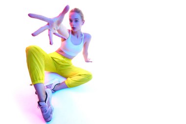 Neon ışıkta giyinmiş neon kıyafetli neşeli genç kadın portresinin altından ellerini kameraya uzatırken. Spor anlayışı, moda, aktif yaşam tarzı, gençlik, reklam. Boşluğu kopyala