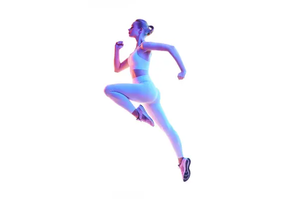 在霓虹灯下 年轻的动作片女主人公在白色背景下独立地奔跑 热身运动 健康的生活方式 广告的概念 复制空间 — 图库照片