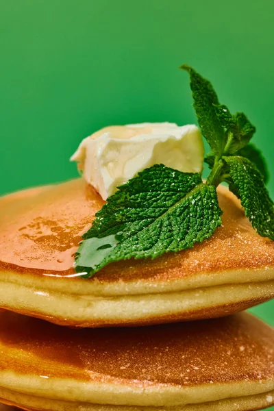 Food pop art photography. Close up. Sweet pancakes with maple syrup and batter over green background. Vintage, retro 80s, 70s style. Complementary colors. Concept of food, fashion, style, taste. Ad