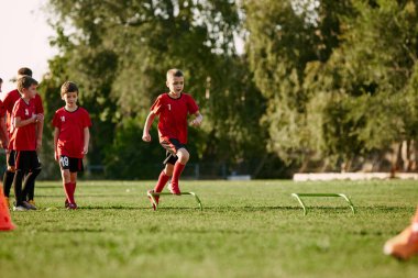 Çocuk portresi, spor üniformalı futbolcu spor yapıyor, antrenman yapıyor, futbol sahasındaki engellerle antrenman yapıyor. Spor envanteri kavramı, aktivite. Ad