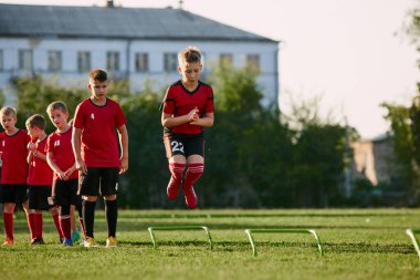 Çocuk portresi, spor üniformalı futbolcu spor yapıyor, antrenman yapıyor, futbol sahasında futbol engelleriyle atlıyor. Spor envanteri kavramı, aktivite. Ad