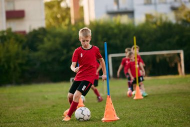 Spor üniformalı okul oyuncusunun yakın çekimde futbol sahasında top sürüşü hareketli. Futbol oynuyordum. Çocuklar takım oyunu. Spor yaşam tarzı, aktivite, hobi anlayışı. Ad