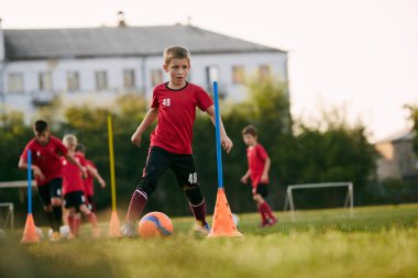 Futbol sahasında spor üniformalı antrenman topu giymiş küçük bir çocuğun portresi. Futbol oynuyordum. Çocuklar takım oyunu. Spor yaşam tarzı, aktivite, hobi, egzersiz kavramı. Ad.