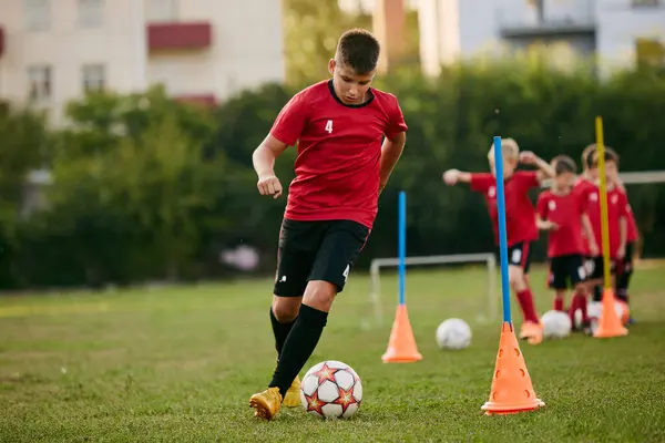 Close up portrait of school soccer player running dribbles ball on sport, football field on match in motion. Playing football. Childrens team games. Concept of sport lifestyle, activity, hobby. Ad.