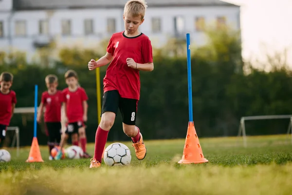 Little boy, soccer player in sport uniform training dribble ball, prepare to match on football field in motion. Playing football. Childrens team games. Concept of sport lifestyle, activity, hobby. Ad