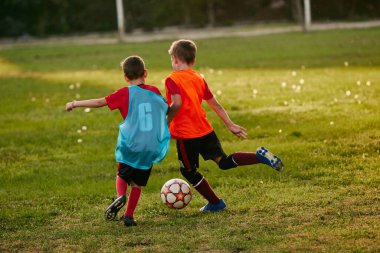 Rekabetçi çocuklar, formalı ve kramponlu spor üniformalı koşucular. Çocuklar futbol sahasında futbol oynarlar. Çocuklar okul takımı. Spor anlayışı, sağlıklı yaşam tarzı, aktivite, hobi.