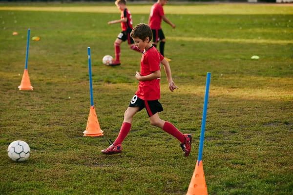 赤いスポーツユニフォームトレーニングショット ストロークのボーイサッカー選手は 運動中のフットボールフィールドにマッチする準備をします サッカーをする 子供のチームゲーム スポーツライフスタイル アクティビティ 趣味の概念 アドベンチャー — ストック写真