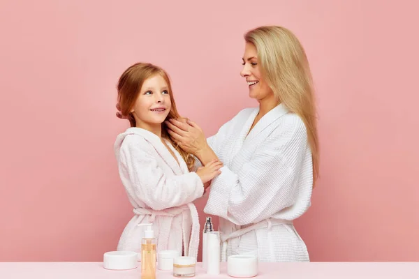 Portrait of lovely mother with daughter hair care in bathroom. Woman and child together care of beauty, health. Cosmetics and wellness of skin. Concept of beauty, spa treatment, self care. ad