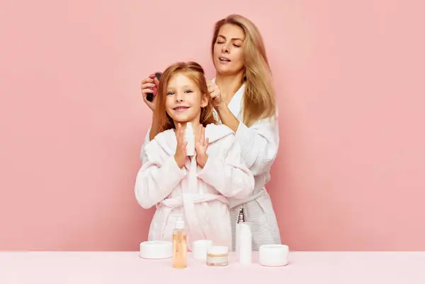 Portrait of lovely mother with daughter hair care in bathroom with natural cosmetic products. Woman and kid together care of beauty, health. Concept of beauty, spa treatment, self care, wellness. ad