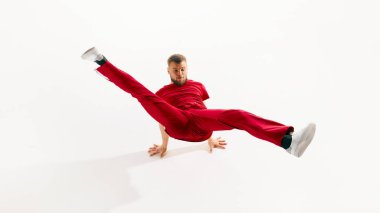 Şık giyimli genç bir adam, serbest dans eden profesyonel bir dansçı, break dans öğeleri, beyaz stüdyo geçmişine karşı esneme. Gençlik kültürü, spor, yaşam tarzı kavramı. Uzayı kopyala ad