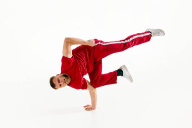 Şık giyimli genç bir adam, serbest dans eden profesyonel bir dansçı, break dans elemanları, beyaz stüdyo arka planına karşı donuyor. Kentsel, gençlik kültürü, spor, aktif yaşam tarzı konsepti. Boşluğu kopyala