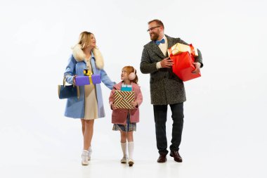 İyi tatiller. Mutlu, neşeli ve çocuklu bir çift beyaz arka planda eski moda kıyafetler giyiyor. Hediyeli hoş bir aile arkadaşlarına gider. Noel konsepti, yeni yıl. Boşluğu kopyala