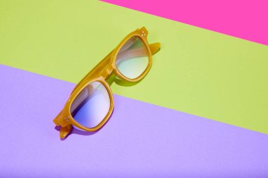 Poster. Podyumlardaki plastik çerçeveli güneş gözlükleri renkli parlak arkaplanlara karşı. Moda yaz aksesuarları. Güzellik anlayışı, trendler, satışlar, alışveriş. Uzayı kopyala Reklam. Pankart için, web hattı.