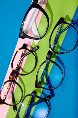 Poster. Optik mağaza indirimi. Düz yatıyordu. Plastik çerçevelerdeki farklı gözlüklerin renkli parlak arkaplanlarla yakın plan fotoğraflarını çek. Moda aksesuarları. Cazibe, satış, alışveriş kavramı. Ad