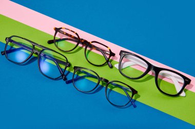 Poster. Optik mağaza indirimi. Düz yatıyordu. Plastik çerçevelerdeki farklı gözlüklerin renkli parlak arkaplanlarla yakın plan fotoğraflarını çek. Moda aksesuarlar. Cazibe, tarz, moda, alışveriş anlayışı. Ad