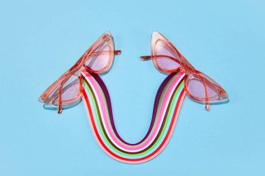 Poster. Optik mağaza indirimi. Plastik pembe çerçeveli gözlüklerin fotoğrafını parlak arka planda renkli elementlerle karşılaştır. Moda aksesuarlar. Cazibe, tarz, moda, alışveriş anlayışı. Ad