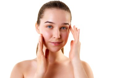 Çıplak omuzlu, yüzüne dokunan kameraya bakan güzel ve genç bir kadın. Cilt bakımı kozmetik tedavi etkisi. Cilt rutini. Gençlik kavramı, doğal güzellik, sağlıklı, kozmetoloji.