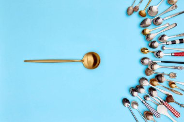 Çatal bıçak takımı. Üst manzara fotoğrafı. Mavi stüdyo arka planında çeşitli antika gümüş çatal bıçak ve altın kaşıklarla çevrili çorba kaşığı. Yemek kavramı, tatil, sofra kurma, retro, vintage