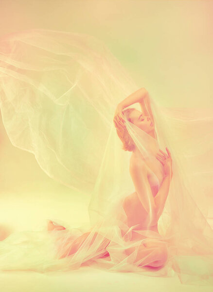 Sentimentality, delicacy. Beautiful sensitive girl sitting on floor alone covered transparent fabric. Highlights. Retro pastel color palette. Natural beauty of female body concept. Highlights effect