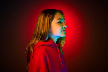 Sakin bir genç erkek, kız, kırmızı kapüşonlu bir öğrenci karışık renkli neon filtreli bir arka plan. Gençlik kavramı, duygular, güzellik, moda, tarz, trendler. ad