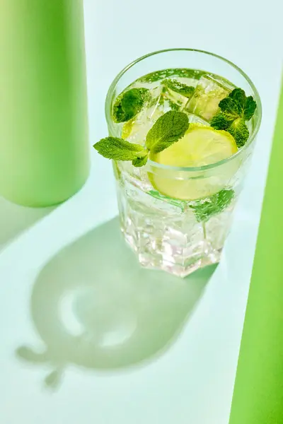 Poster. Top view photo of lemonade with lime slices and mint against vibrant contemporary colored studio background. Concept of summer refreshing, invigorating zest. Fresh twist, vibrant charm