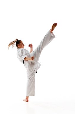 Dikiz aynası. Kadın profesyonel karate dövüşçüsü beyaz arka planda izole edilmiş hareket halinde tekme atıyor. Spor, eğlence, sanat, hobi, kültür kavramı. İlan, metin için boşluk kopyala.