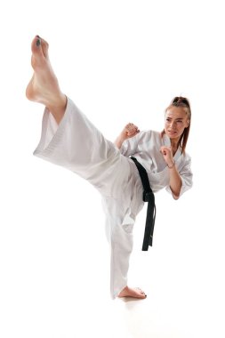 Siyah kuşaklı usta tekvando dövüşçüsü beyaz arka planda yüksek tekme pozu veriyor. Dövüş sanatları. Spor, eğlence, sanat, hobi, kültür kavramı. İlan, metin için boşluk kopyala.