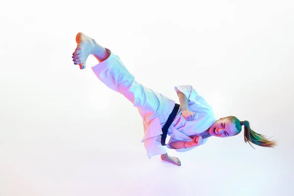Top view portrait of female Taekwondo fighter, teacher performing high kick isolated over white studio background. Concept of professional sport, recreation, art, hobby, culture. Copy space. Fish eye.
