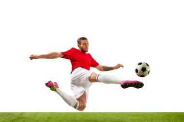 Genç futbolcu yeşil çimlerin üzerinde beyaz arka planda topa tekme atma pratiği yaparken kendinden emin görünüyor. Futbol okulu. Oyun, spor, eğlence, aktif yaşam tarzı kavramı.