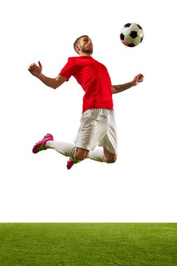 Genç bir adam, kırmızı spor giyimli profesyonel bir oyuncu ve yeşil çimenli beyaz arka plana karşı futbol numaraları yapıyor. Oyun, spor, eğlence, aktif yaşam tarzı kavramı.