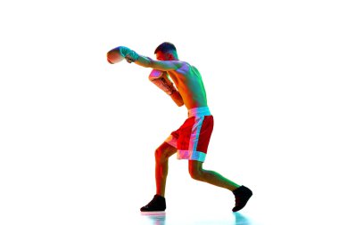 Yan görüş. Aktif üstsüz erkek boksör, karışık dövüş sanatları dövüşçüsü karışık neon filtreli beyaz arka plan, ışık. Spor anlayışı, aksiyon, hareket, sağlıklı yaşam tarzı. İlan için alanı kopyala.