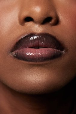 Parlak, Afro-Amerikan kadın dudaklarının aşırı yakın plan fotoğrafı. Dudak parlatıcı ruj. Cilt bakımı rutini. Güzellik, makyaj, kozmetoloji, spa tedavileri, kozmetik ürünler. Ad