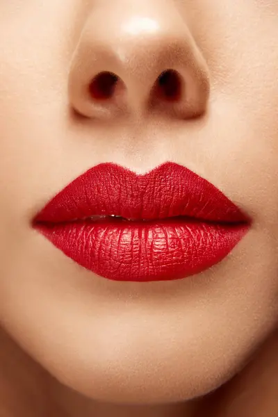Extreme close up photo of full plump bright red female lips. Mouth clothed. Lip matte lipstick. Skin care routine. Concept of beauty, make-up, cosmetology, spa treatments, cosmetic products. Ad